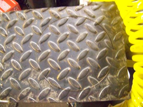 1989 Ford Bronco - A close-up view of diamond plate metal, possibly a step or floor panel, with a yellow coil spring nearby.