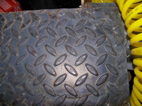 1989 Ford Bronco - A close-up view of diamond plate metal with a circular cutout and a yellow coiled hose is visible.