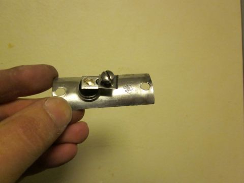 1979 Ford Bronco - A close-up of a metal bracket with a screw, held by a person's hand.