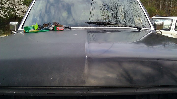 1989 Ford Bronco hood with cleaning supplies and another vehicle in the background