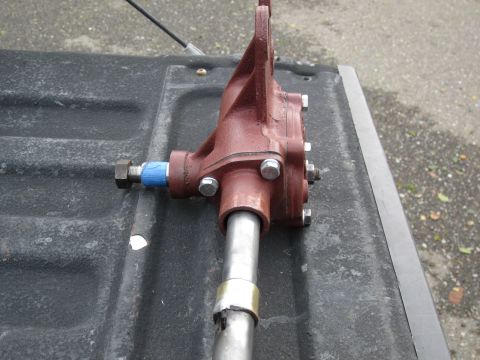 1979 Ford Bronco - Close-up of a red steering box with a metal shaft, placed on a dark, textured surface.