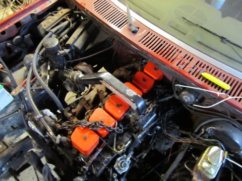 1984 Ford Bronco - Close-up view of an engine bay, bright orange valve covers and various engine components.