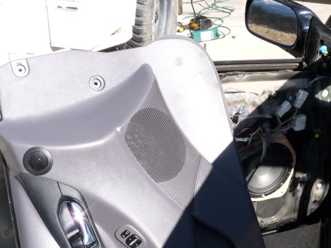 2006 Ford E350 - The interior of a car door is disassembled, showing the speaker and wiring behind the panel.
