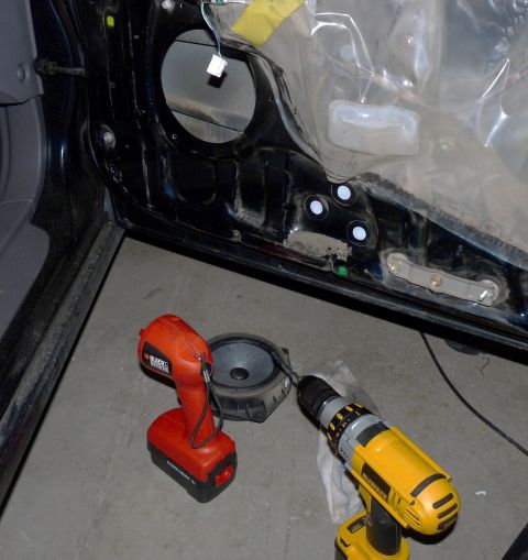 2006 Ford E350 - Car door interior with speaker removed, two drills on the floor.