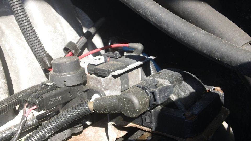 Engine bay wiring harness connectors and coil pack close-up on a Ford