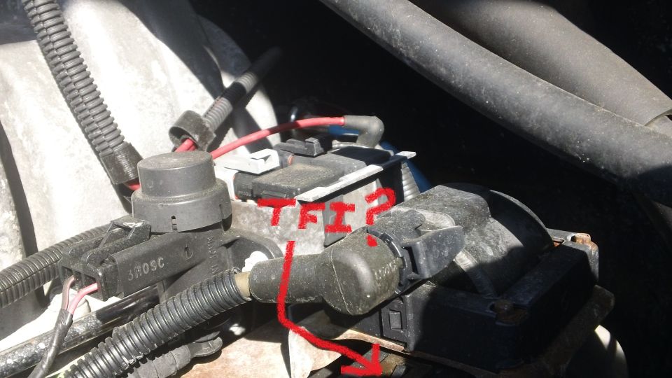 Engine bay close-up with red TFI? arrow pointing at ignition module on a Ford distributor