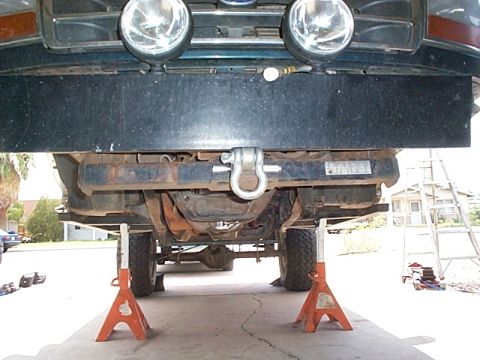 1994 Ford Bronco - The front of a vehicle is elevated on jack stands, showing its undercarriage and tow hitch assembly.