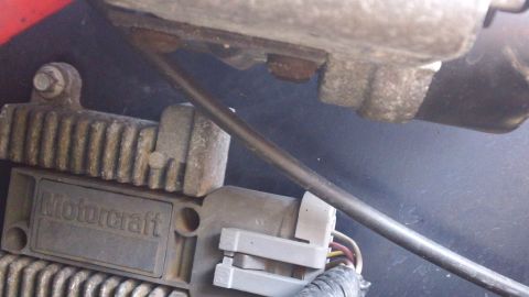 1994 Ford Bronco - Close-up of a Motorcraft ignition control module mounted to a finned aluminum heat sink on a dark inner fender, with its gray and white con…