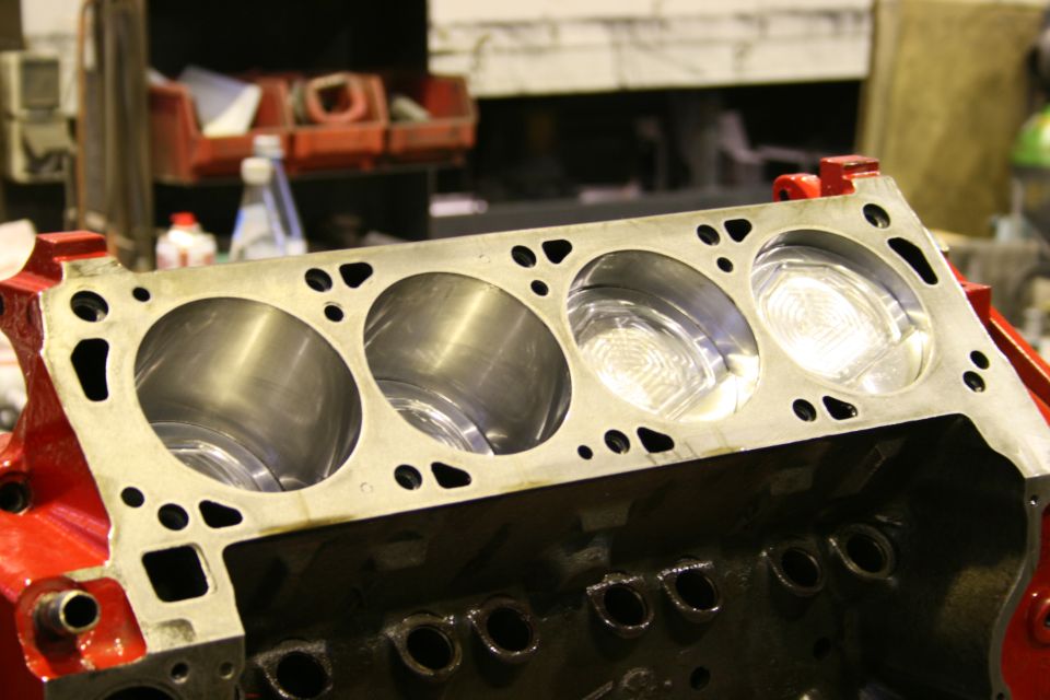 Engine block with four cylinders and pistons visible, red and black paint