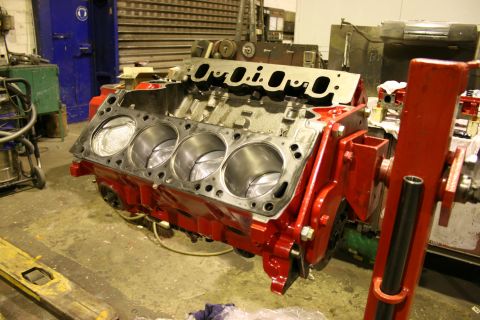 1973 Ford Ranchero - A disassembled V8 engine block is mounted on a red stand in a workshop setting.