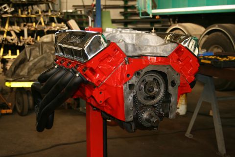 1973 Ford Ranchero - V8 engine with chrome valve covers and headers, mounted on a stand in a workshop.
