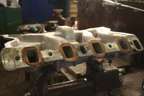 1973 Ford Ranchero - An intake manifold is held in a vise, ready for installation or repair.