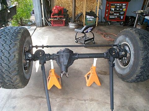 1994 Ford Bronco - Dana 44 front axle assembly with tires, supported by jack stands in a workshop setting.