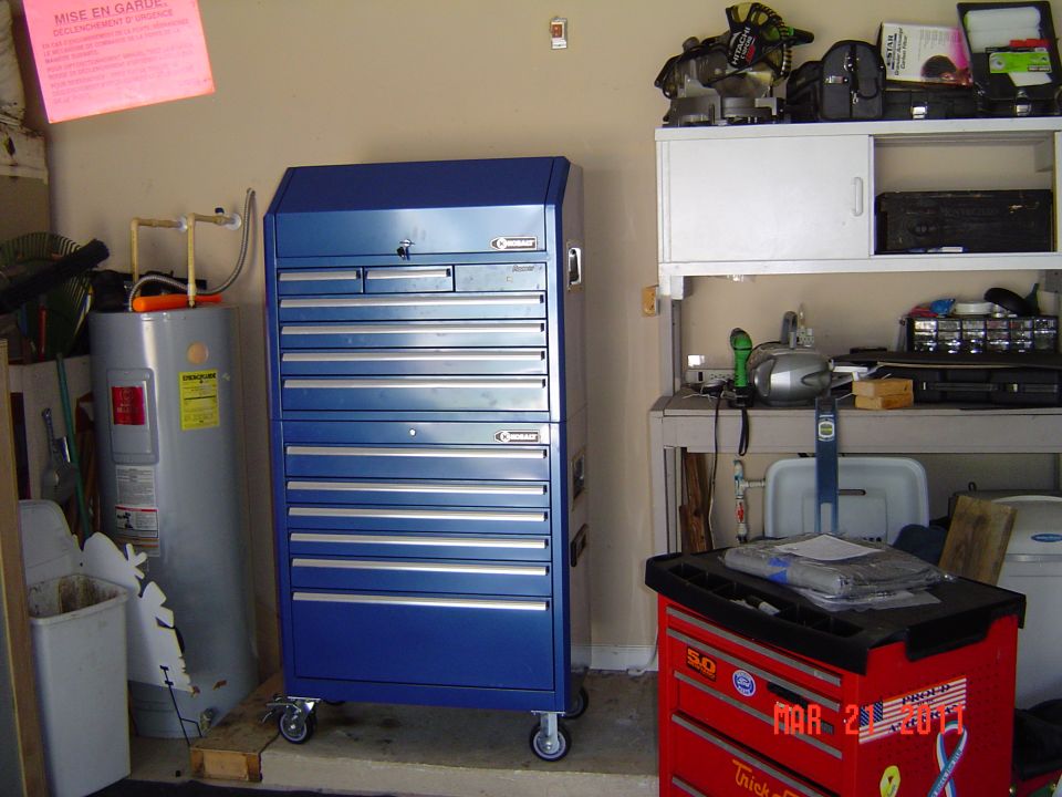 Blue rolling tool chest next to a water heater, with shelves and tools in background