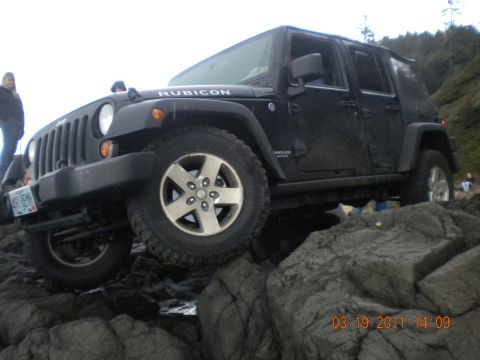 2005 Jeep Wrangler - A black Jeep Wrangler Rubicon navigates a rocky coastal terrain.