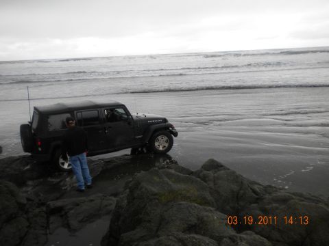 2005 Jeep Wrangler - A black Jeep Wrangler is parked on a rocky shoreline with waves crashing in the background.