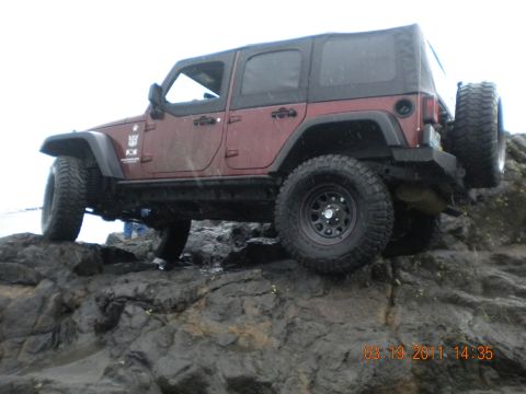 2005 Jeep Wrangler - A red Jeep Wrangler navigates a rocky terrain, with a timestamp of 03.19.2011 visible.