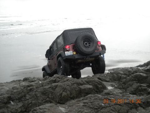 2005 Jeep Wrangler - Jeep Wrangler navigating rocky terrain near the ocean shoreline.