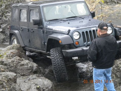 2005 Jeep Wrangler - A man watches a Jeep Wrangler Rubicon drive through a rocky, wet path. The timestamp 03.19.2011 is visible.