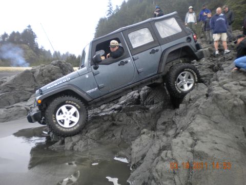 2005 Jeep Wrangler - Jeep Wrangler Rubicon navigating rocky terrain on a beach, with onlookers present.