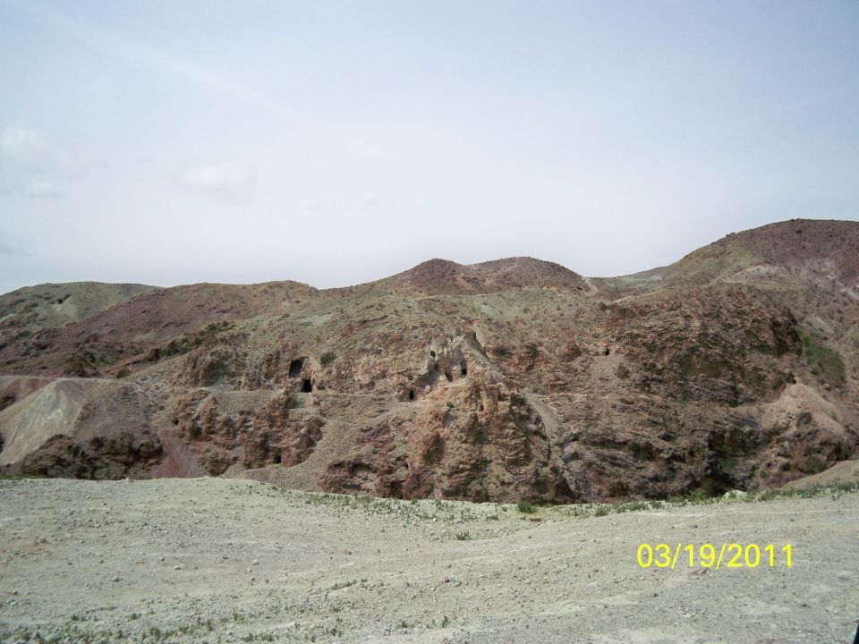 Rocky hills with caves under a hazy sky, timestamped 03/19/2011