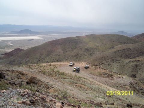 1992 Jeep Wrangler - A group of off-road vehicles are stopped on a trail in a mountainous desert landscape.