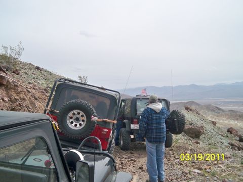 1992 Jeep Wrangler - Two Jeep Wranglers navigate a steep, rocky terrain with a vast, hazy valley in the background.