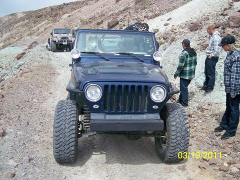 1992 Jeep Wrangler - Two Jeeps navigate a rocky trail, with people observing the off-road adventure.