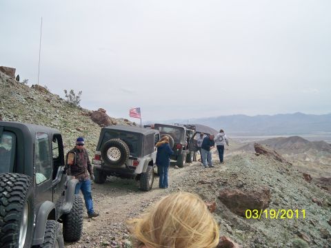 1992 Jeep Wrangler - A convoy of Jeep Wranglers navigates a desert trail under an overcast sky.