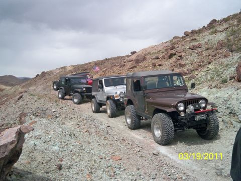 1992 Jeep Wrangler - A convoy of Jeeps navigates a desert trail, led by a brown Jeep CJ-7.