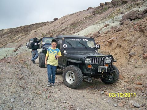 1992 Jeep Wrangler - Several Jeep Wranglers are parked on a rocky, off-road trail in a desert landscape.
