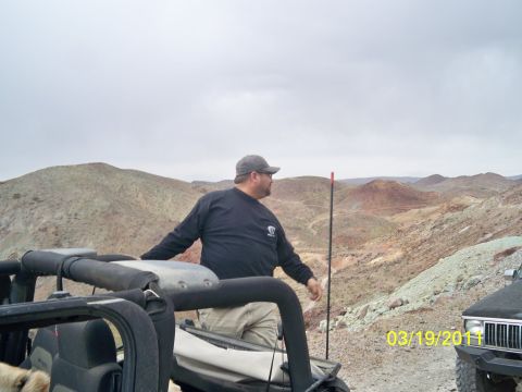 1992 Jeep Wrangler - A man in a black Jeep surveys a desert terrain with mountains in the background.