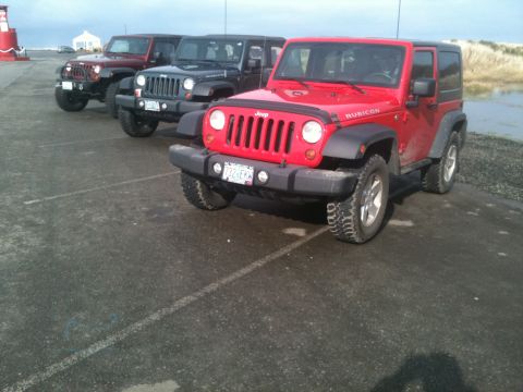 2005 Jeep Wrangler - Multiple Jeep Wranglers are parked in a line on a paved surface next to a body of water.
