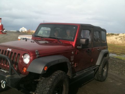 2005 Jeep Wrangler - A red Jeep Wrangler is parked outdoors with a lighthouse and building in the background.