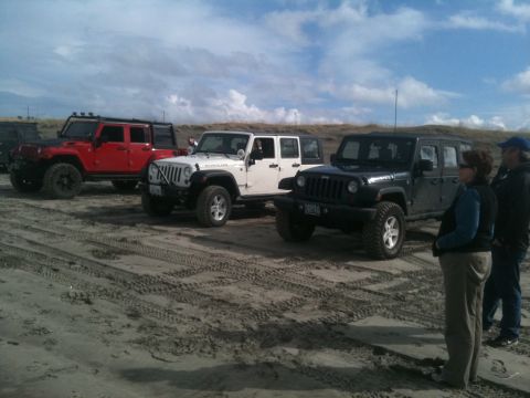 2005 Jeep Wrangler - Multiple Jeep Wranglers are parked on a sandy beach under a cloudy sky.