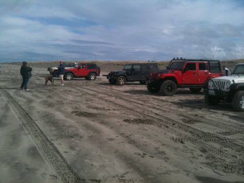 2005 Jeep Wrangler - A group of Jeep Wranglers are parked on a sandy beach under a cloudy sky.