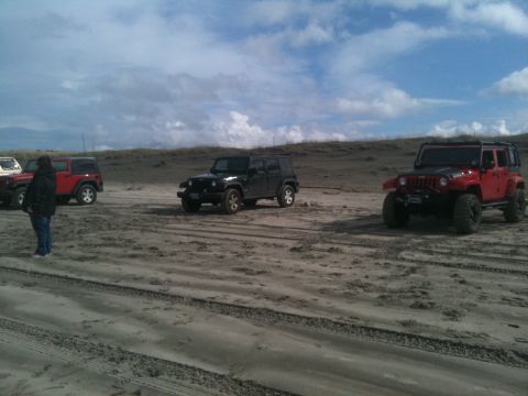 2005 Jeep Wrangler - Multiple Jeep Wranglers are parked on a sandy terrain under a cloudy sky.