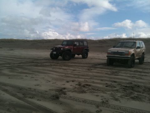 2005 Jeep Wrangler - Two SUVs are parked on a sandy beach with tire tracks visible in the foreground.
