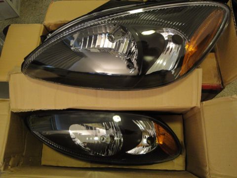 2003 Ford Taurus - Two black headlights for a 2003 Ford Taurus are shown in their packaging.
