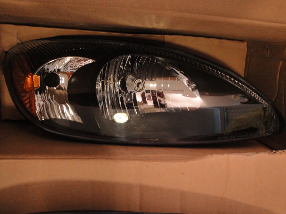 New black-housing teardrop headlight assembly with amber marker sitting in a cardboard box
