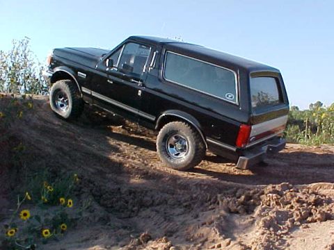 1989 Ford Bronco - This black 1989 Ford Bronco is captured mid-climb on a dusty, uneven terrain.