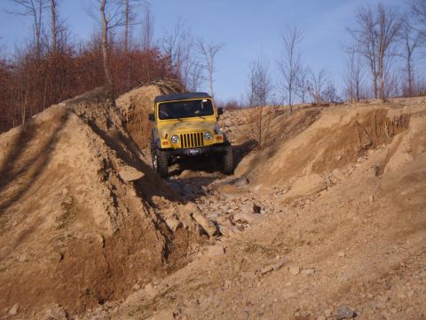2003 Jeep Wrangler - A yellow 2003 Jeep Wrangler navigates a challenging off-road course.