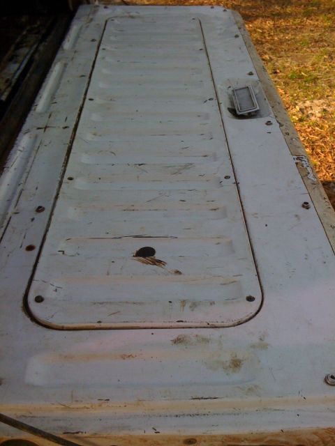 1992 Ford C-350 (Centurion Conversions) - Close-up of a white tailgate a recessed panel and a handle, showing signs of wear.