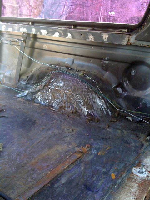 1992 Ford C-350 (Centurion Conversions) - The rear interior floor of a vehicle shows extensive rust and exposed wiring, indicating significant wear or disrepair.