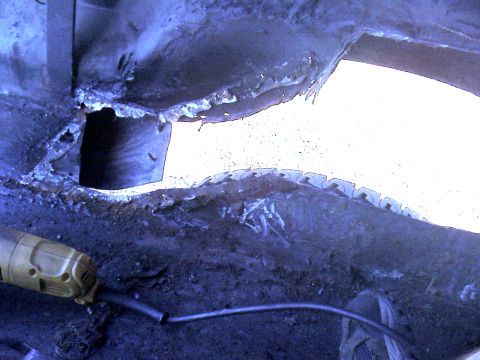 1992 Ford C-350 (Centurion Conversions) - Metal cutting in progress on a vehicle's undercarriage, showing rust and damage.