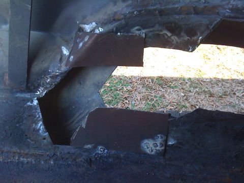 1992 Ford C-350 (Centurion Conversions) - Close-up of metal patches welded onto a vehicle's frame, likely for rust repair.