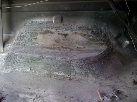 1992 Ford C-350 (Centurion Conversions) - The interior floor of a vehicle shows evidence of rust repair and bodywork, with patched sections and smoothed surfaces.