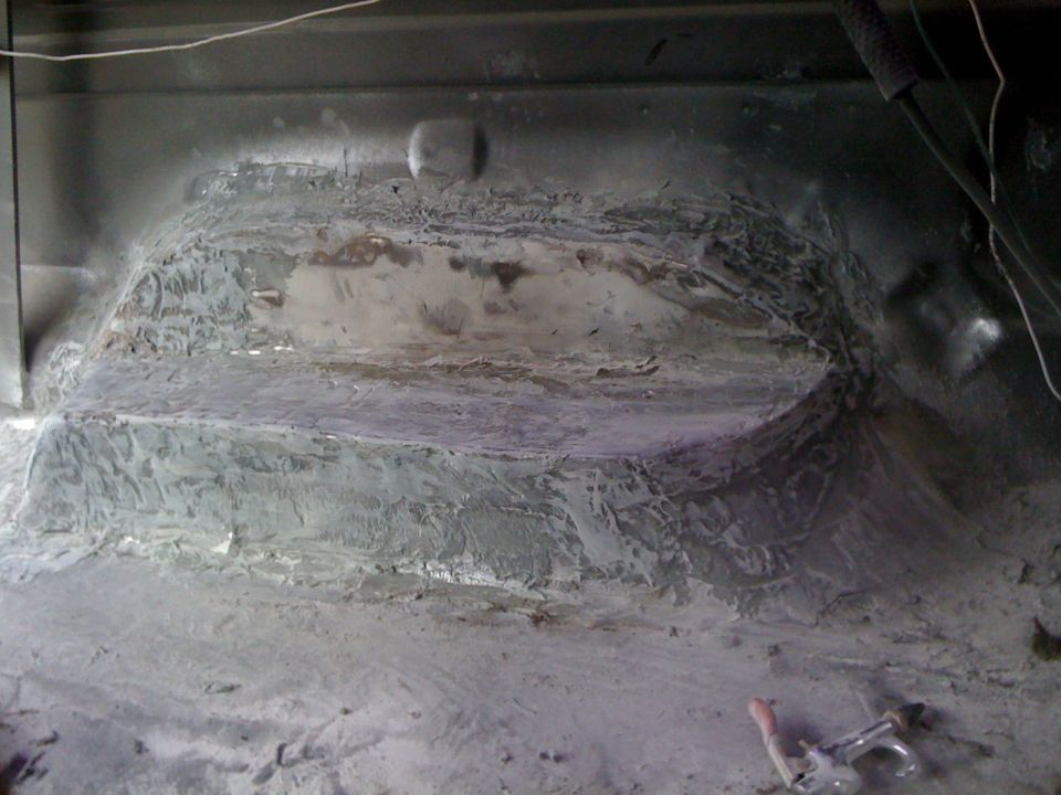 Interior floor of a vehicle undergoing repair, showing patched and smoothed metalwork
