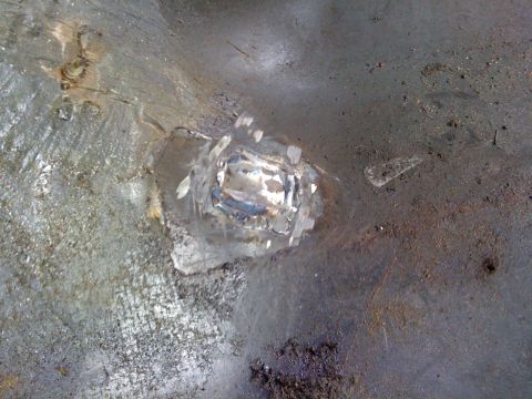 1992 Ford C-350 (Centurion Conversions) - Close-up view of a welded metal patch on the vehicle's floor, indicating repair work in the wheel well or interior area.