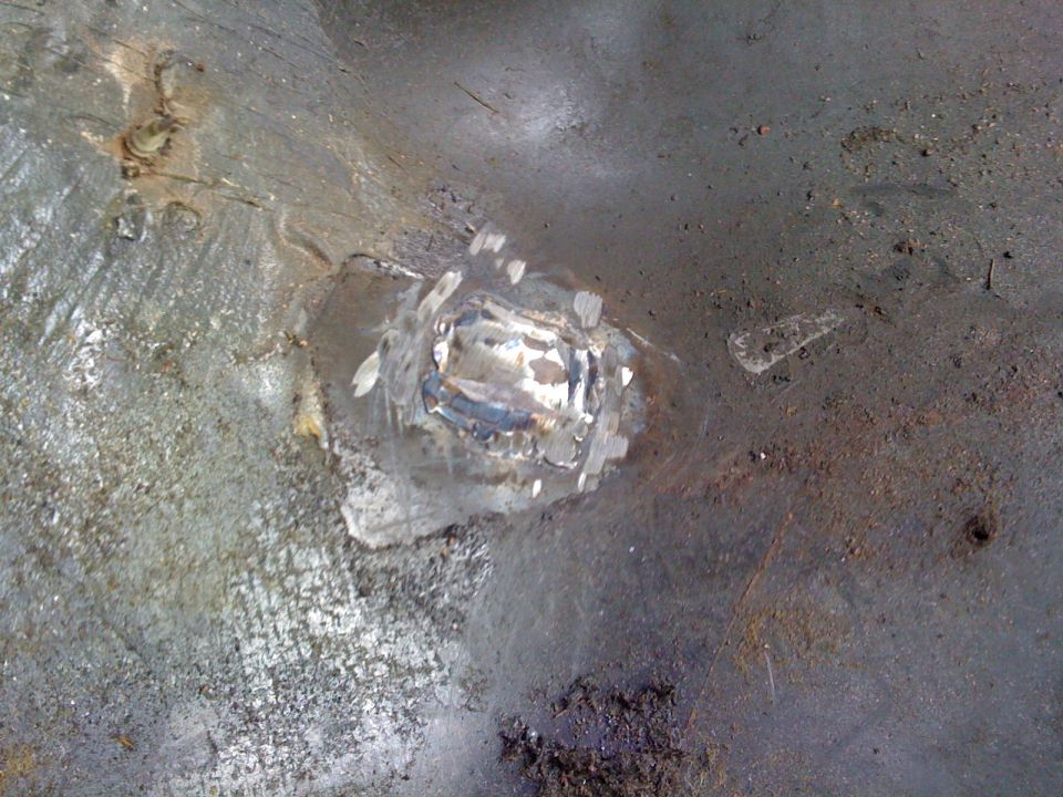 Welded metal patch on vehicle floor, likely repair work